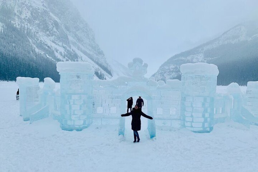 A person standing in front of ice sculptures in a snowy landscape with mountains in the background. 2