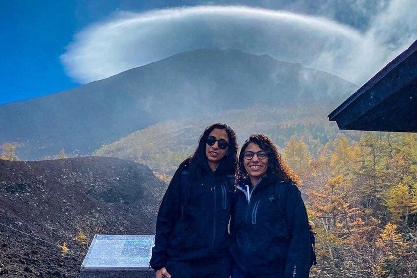 Two people standing in front of a volcanic landscape with a mountain in the background. 2