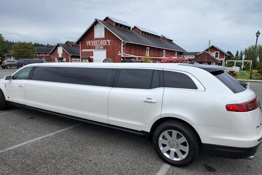A white station wagon parked in a lot with a building labeled 'WHIDBAY 1904' in the background. 2