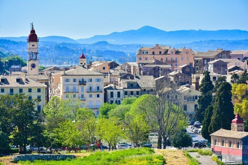 Un pueblo con una imponente torre del reloj, edificios históricos y un paisaje montañoso de fondo. 3