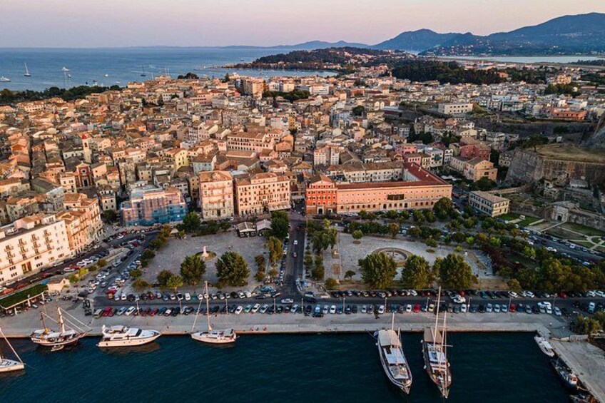 A coastal cityscape with a marina, historic buildings, and a mountainous backdrop. 2