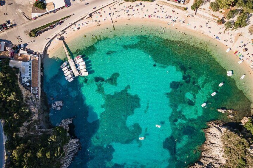Una zona costera con un mar turquesa transparente, un muelle con barcos y una playa arenosa. 2