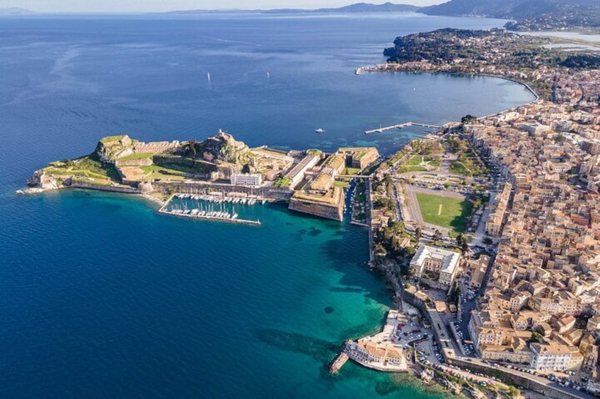 Vista aérea de una ciudad costera con una fortaleza destacada, un puerto deportivo y una zona urbana densamente construida. 1