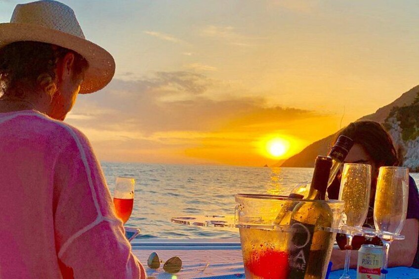 A sunset over the ocean with a person wearing a hat and a pink shirt. 3