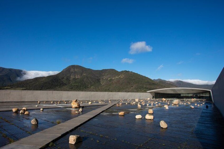 Una azotea con rocas grandes, un edificio moderno y montañas al fondo. 1