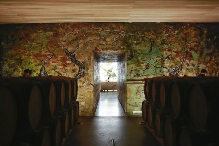 Un espacio interior con techo de madera, una pared con un mural de una rama de árbol y hileras de bancas de madera. 2