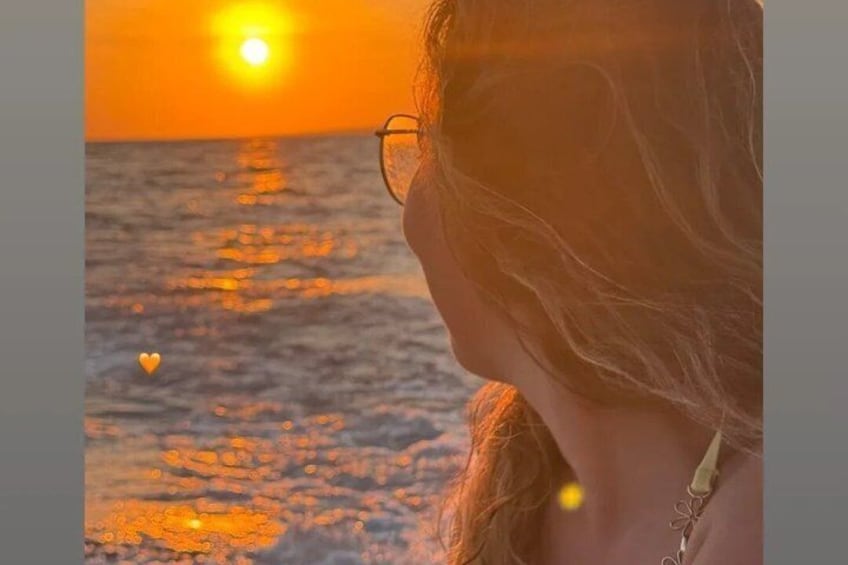 Un atardecer sobre el océano con una persona de espaldas a la cámara. 3