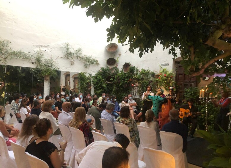 A crowd seated at an outdoor event with a stage and musicians. 2