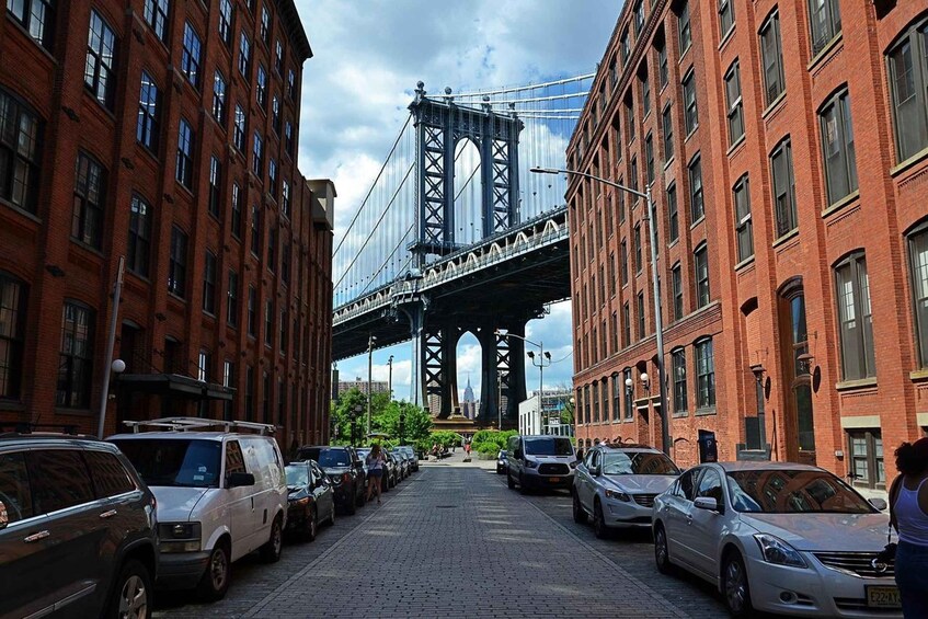 Una calle con coches aparcados y un puente grande al fondo. 4