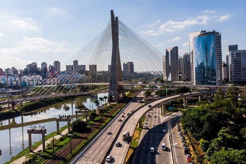 A modern cable-stayed bridge, a city skyline, and a highway with vehicles. 2