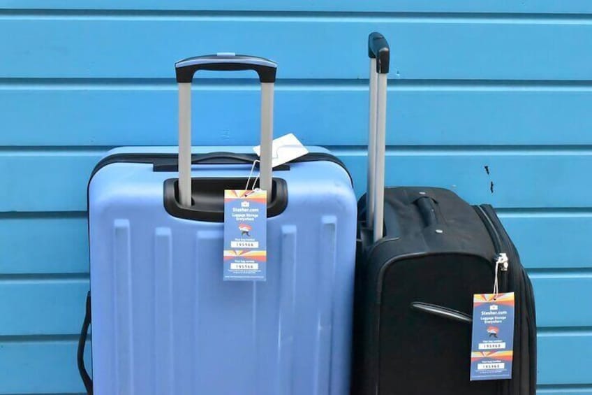 Two suitcases, one blue and one black, with tags against a blue wall. 3