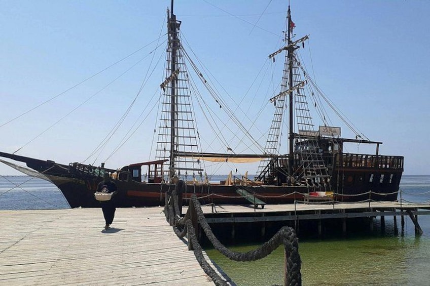 A wooden pier with a large sailing ship docked at the end. 5