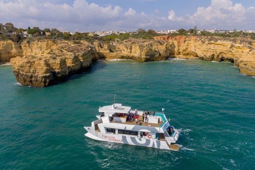 Un barco blanco con pasajeros navegando cerca de una costa rocosa con acantilados. 3