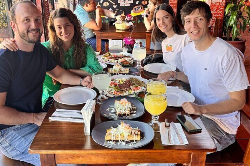 A group of people dining at a restaurant with various dishes and drinks on the table. 1
