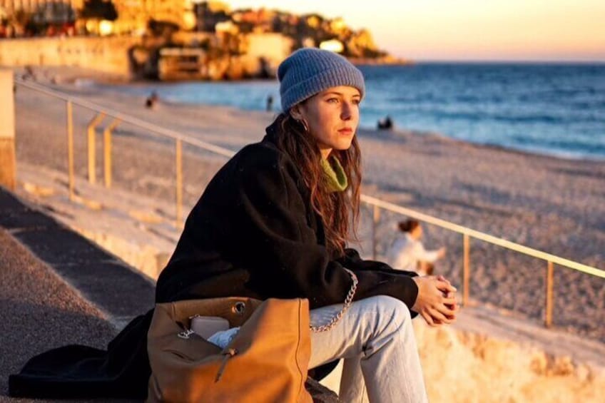 A person sitting on a bench by the seaside during sunset. 1
