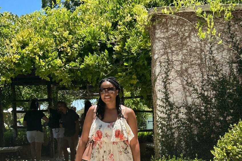 A person standing in front of a tree with a stone structure behind them. 3