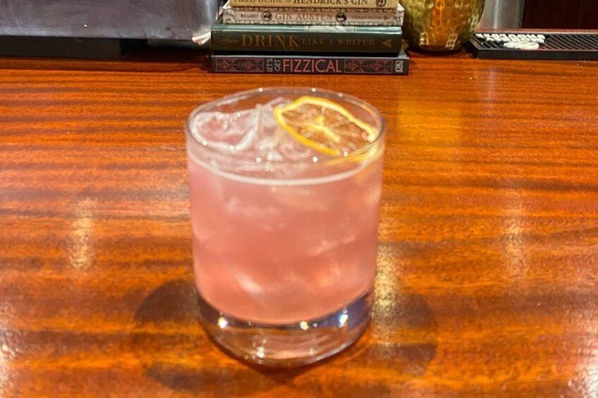 A glass of pink drink with a lemon slice on a wooden table. 2