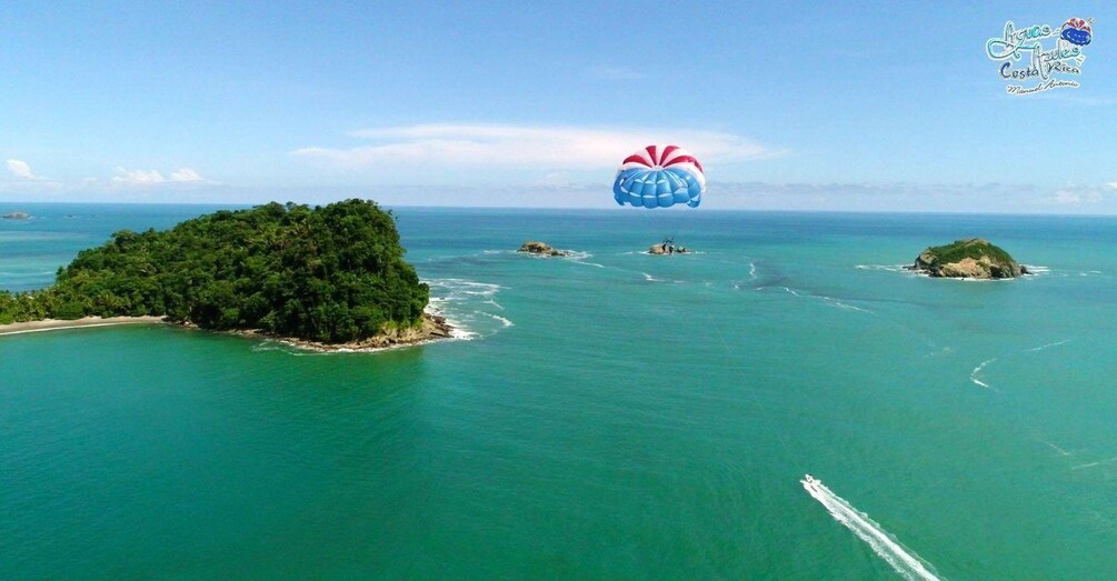 Vista aérea de una isla tropical con aguas turquesas cristalinas, rodeada de islotes más pequeños y una costa distante. 4