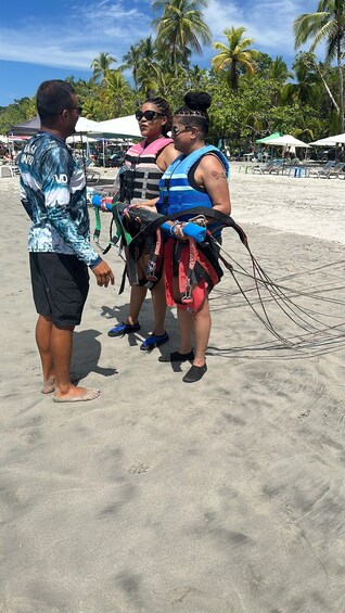 Tres personas en una playa arenosa con palmeras al fondo. 5