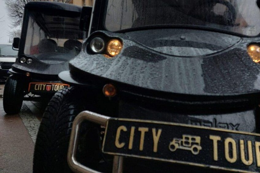 A black vehicle with a license plate reading 'CITY TOUR' and a logo of a city tour bus. 4