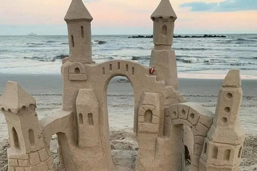 A sandcastle with towers and a bridge at the beach. 3