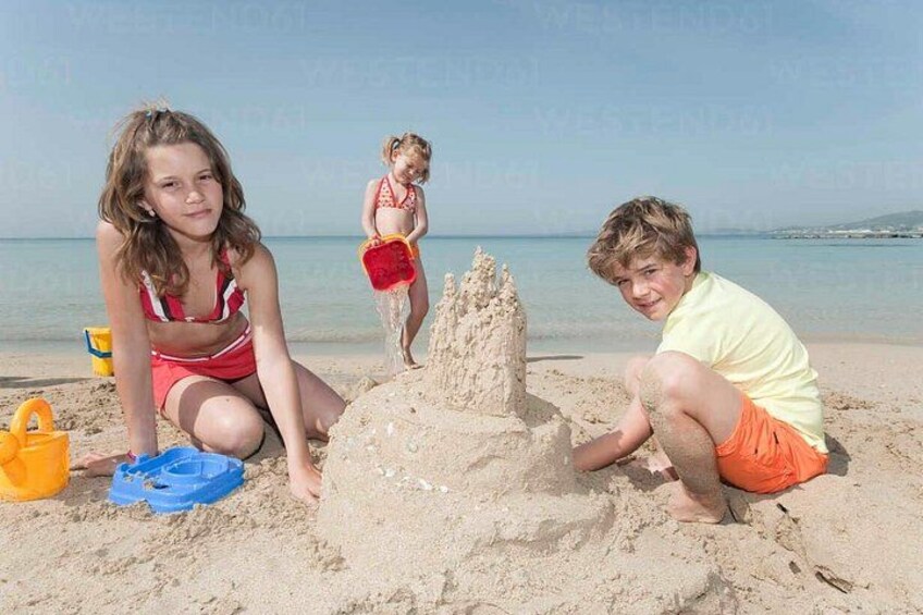 Children playing on a sandy beach with a large sandcastle. 4