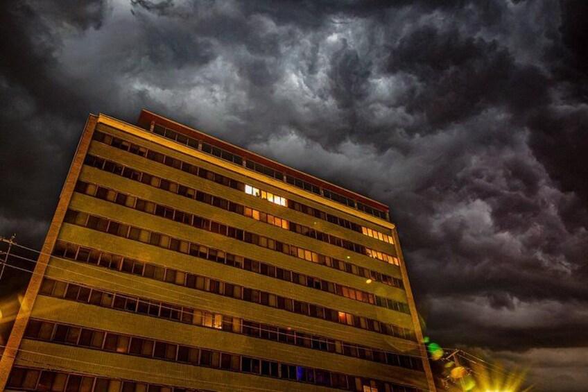Un edificio de varios pisos con ventanas iluminadas bajo un cielo tormentoso. 2
