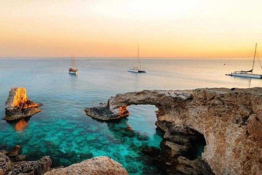A coastal scene with clear turquoise waters, rocky formations, and sailboats. 2