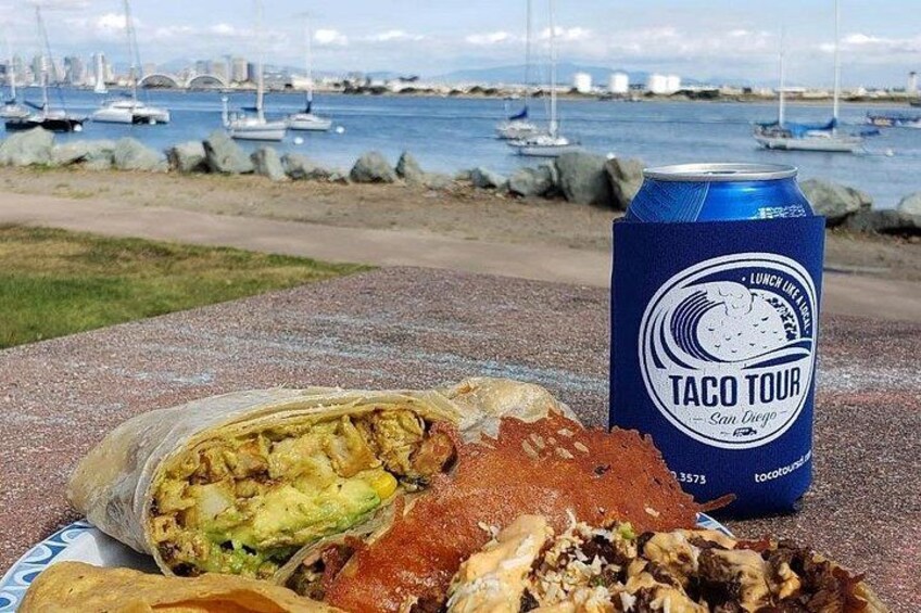 En tallerken med en taco og en drik ved vandet. 4