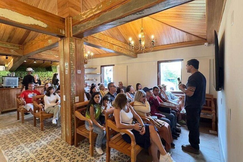 A group of people seated in a wooden room with a speaker addressing them. 2