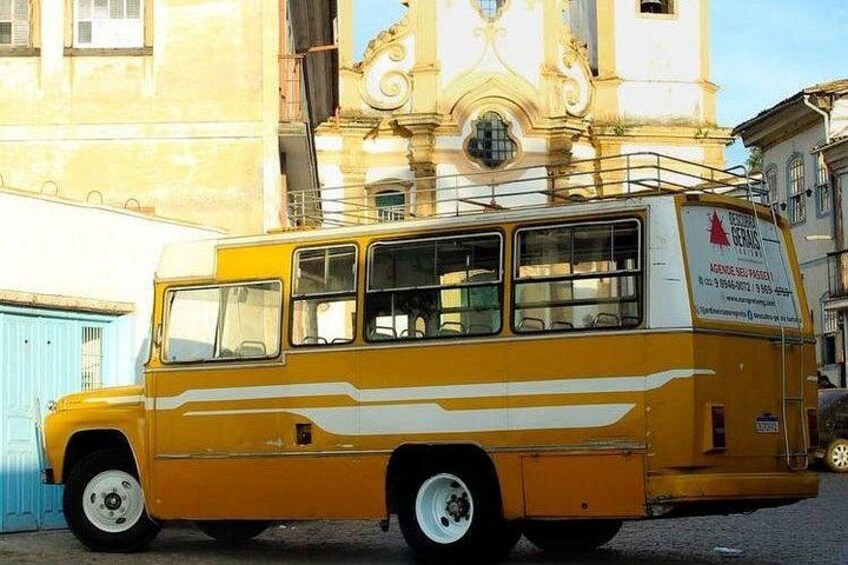 A yellow bus parked in front of a building with a clock tower. 5