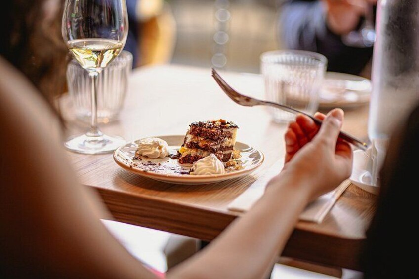 A dining table with a plate of food, a glass of white wine, and a person eating. 3