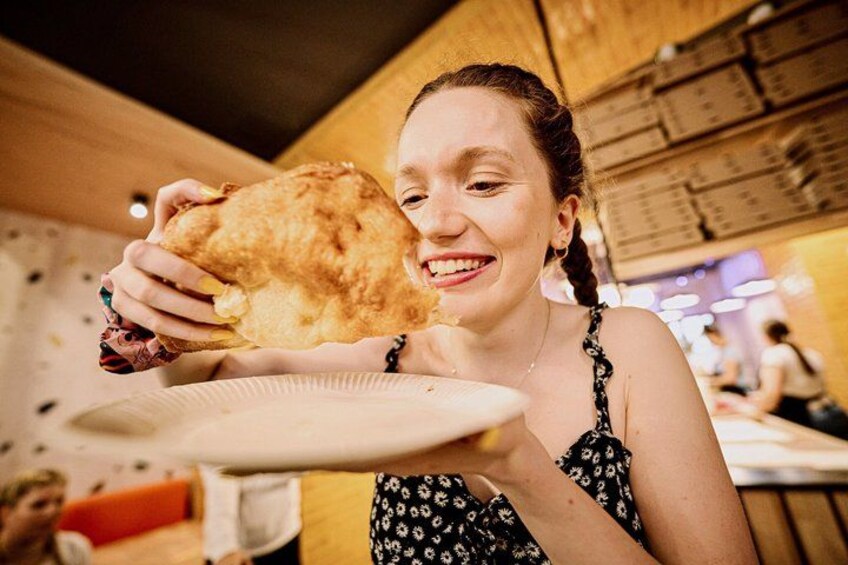 Una persona sosteniendo un alimento frito grande y redondo. 1