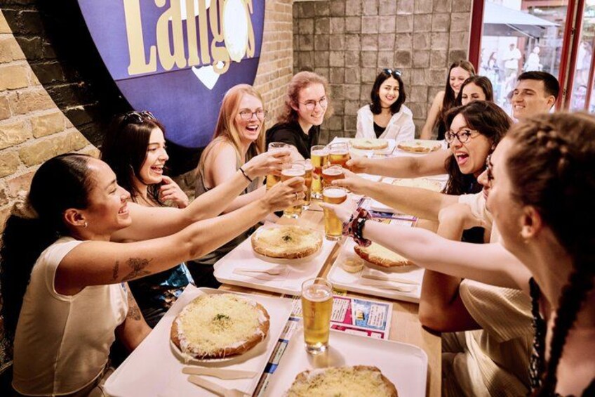 Un grupo de personas brindando con bebidas alrededor de una mesa con comida. 5