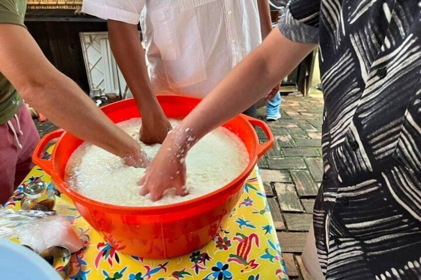 Des personnes qui pétrissent de la pâte dans un saladier rouge posé sur une table. 3