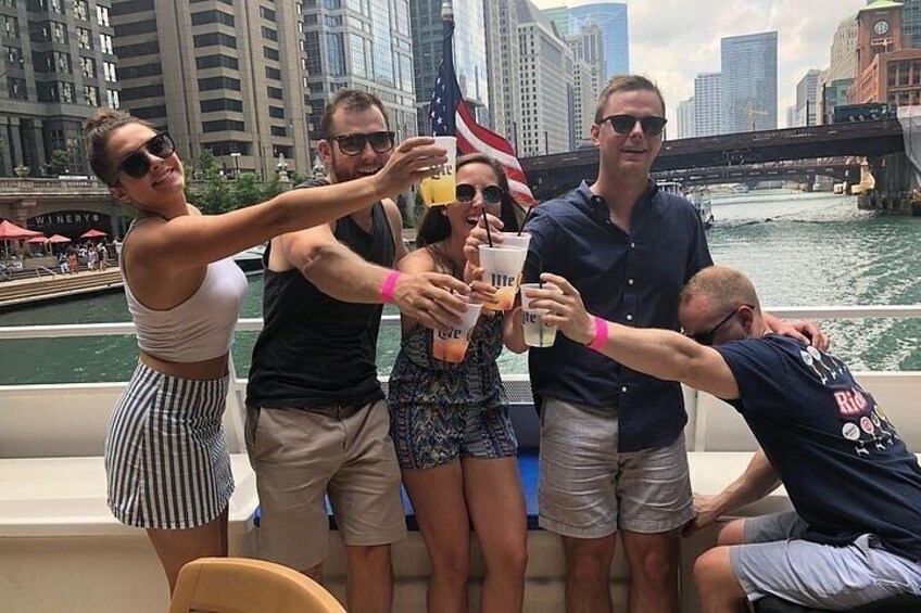 A group of people on a boat, toasting with drinks, with a city skyline and river in the background. 2