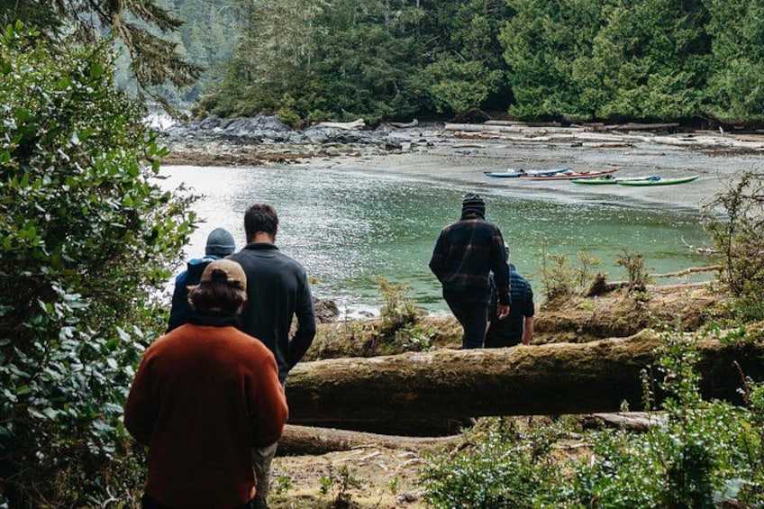 A river with kayaks, people observing, and a forested area. 2