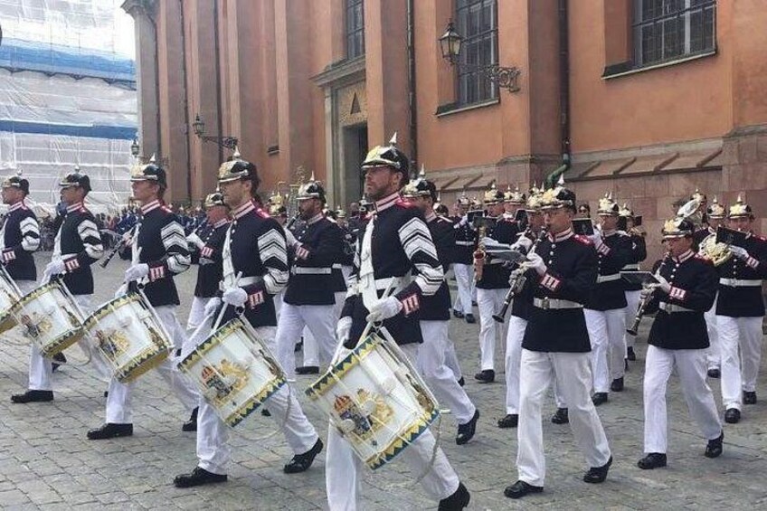 Ett militärorkester som marscherar i formation med trumslagare och bleckblåsinstrument. 5