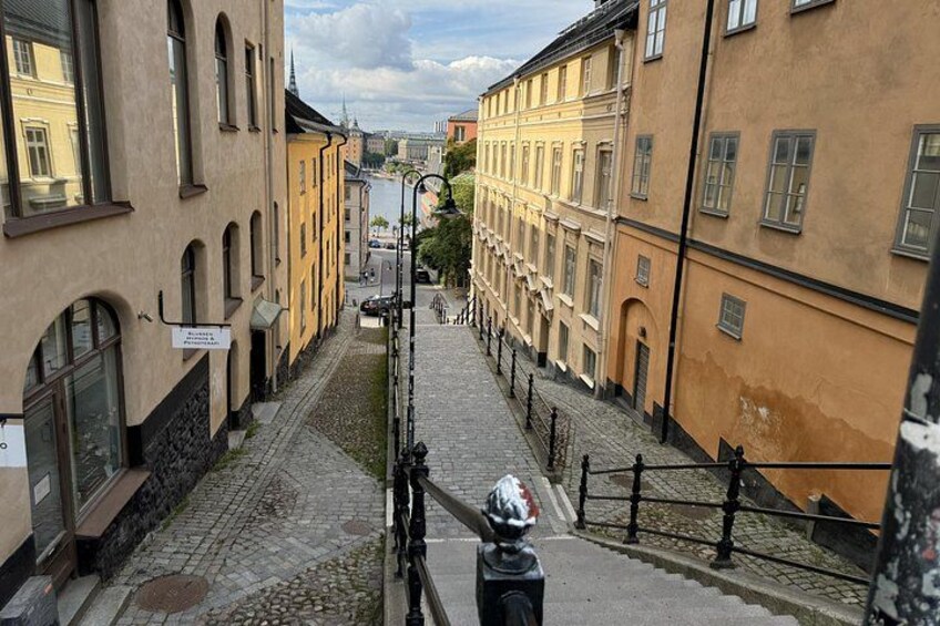 En kullerstensgata omgiven av historiska byggnader med välvda fönster och en klar himmel. 2