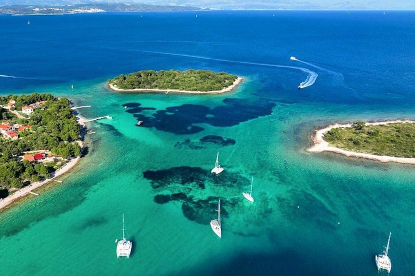 An aerial view of a coastal area with clear turquoise waters, several small islands, and boats anchored in the water. 2