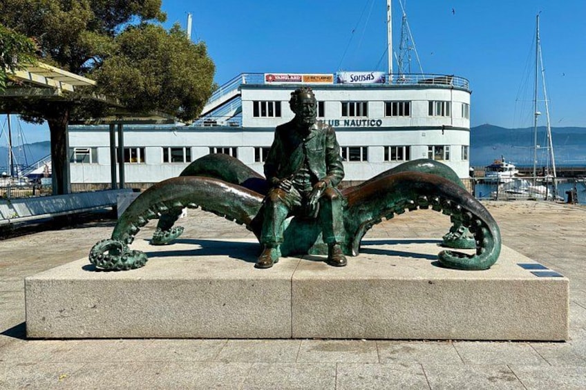 En statue af en mand med en stor fisk ved siden af en bygning, hvor der står 'Club Nautico'. 2