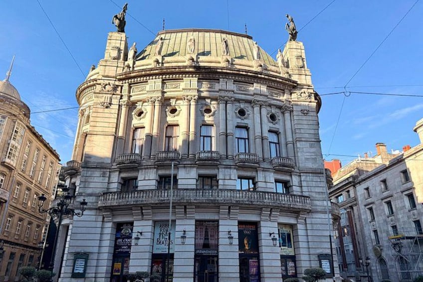 En historisk bygning med detaljeret arkitektur, herunder en kuppel og statuer på taget. 4