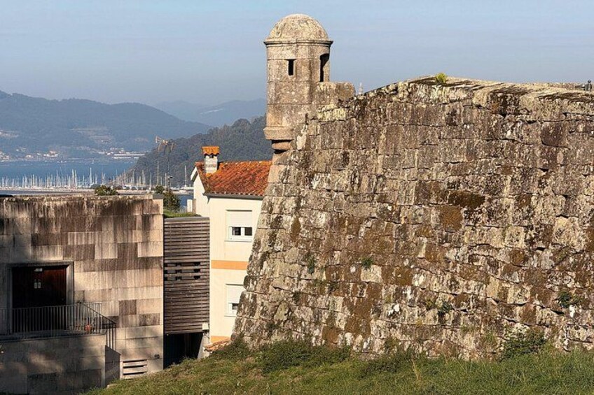 Une fortification en pierre dotée d’une tour de guet, un bâtiment moderne avec un toit rouge et, en arrière-plan, une vue sur la côte. 5