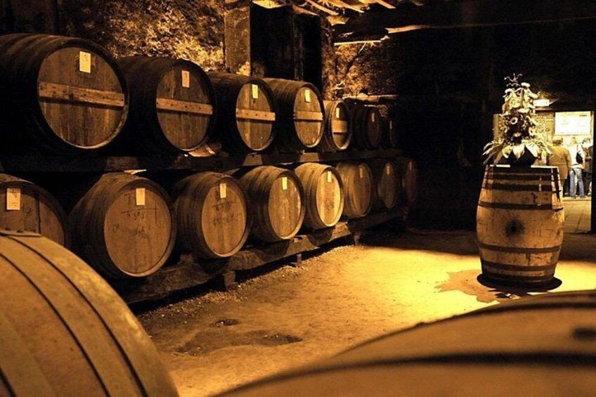 Des barriques en bois sont empilées à l’intérieur, probablement dans un entrepôt ou un lieu de stockage et d’affinage. 5