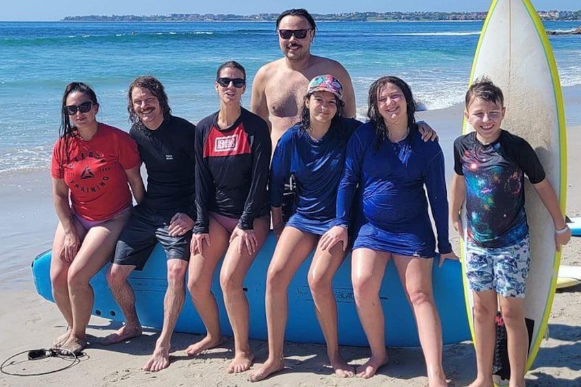 Un groupe de personnes est assis sur un matelas gonflable bleu sur une plage, et une planche de surf est appuyée contre le matelas. 5