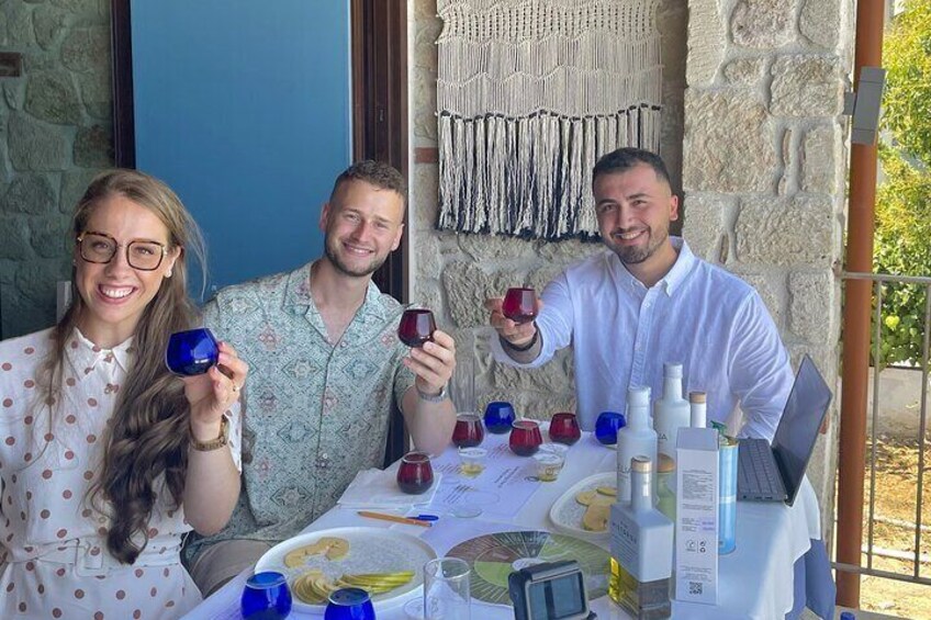 Three people at a table with wine glasses, a laptop, and various bottles. 3