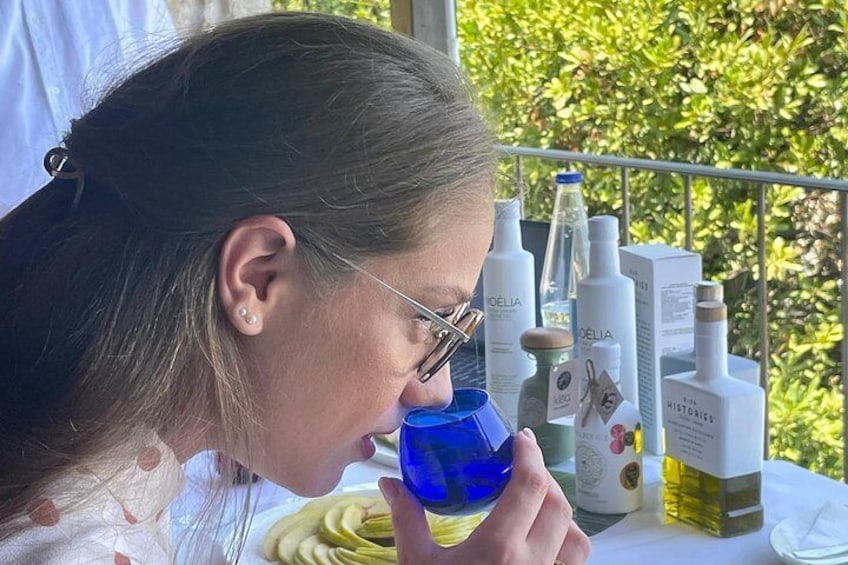 Una persona sosteniendo un vaso azul, con productos para el cuidado de la piel sobre una mesa. 4