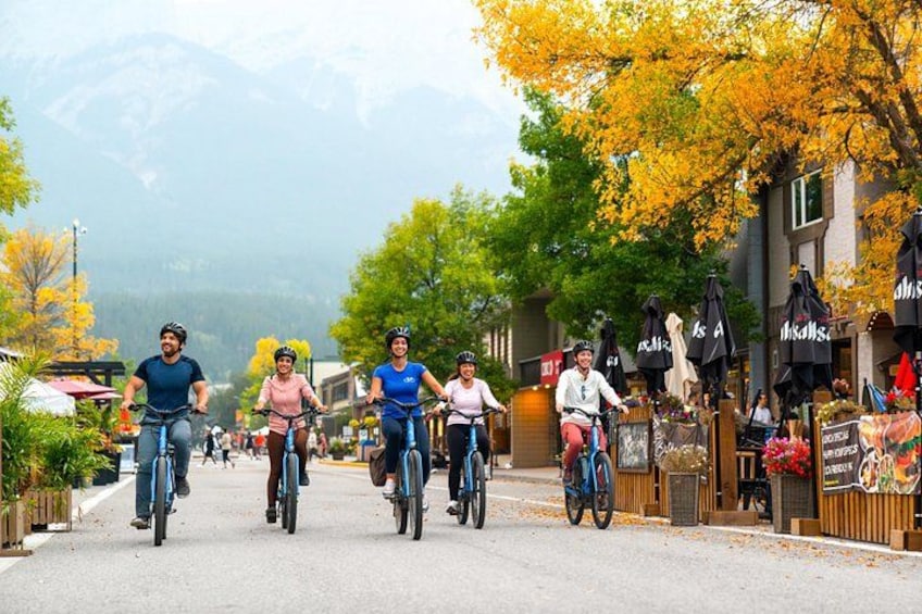 Cyclists on a street with autumn trees and mountains in the background. 2