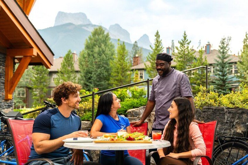 A group of people dining outdoors with a mountain backdrop. 4