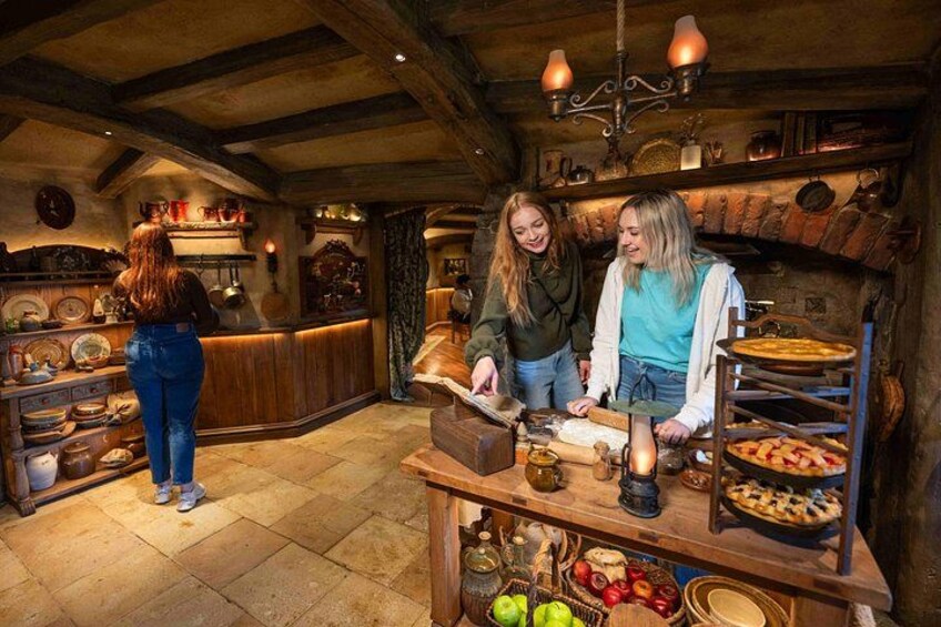 A rustic kitchen with wooden beams, a stone floor, and a wooden counter with various kitchen items. 1
